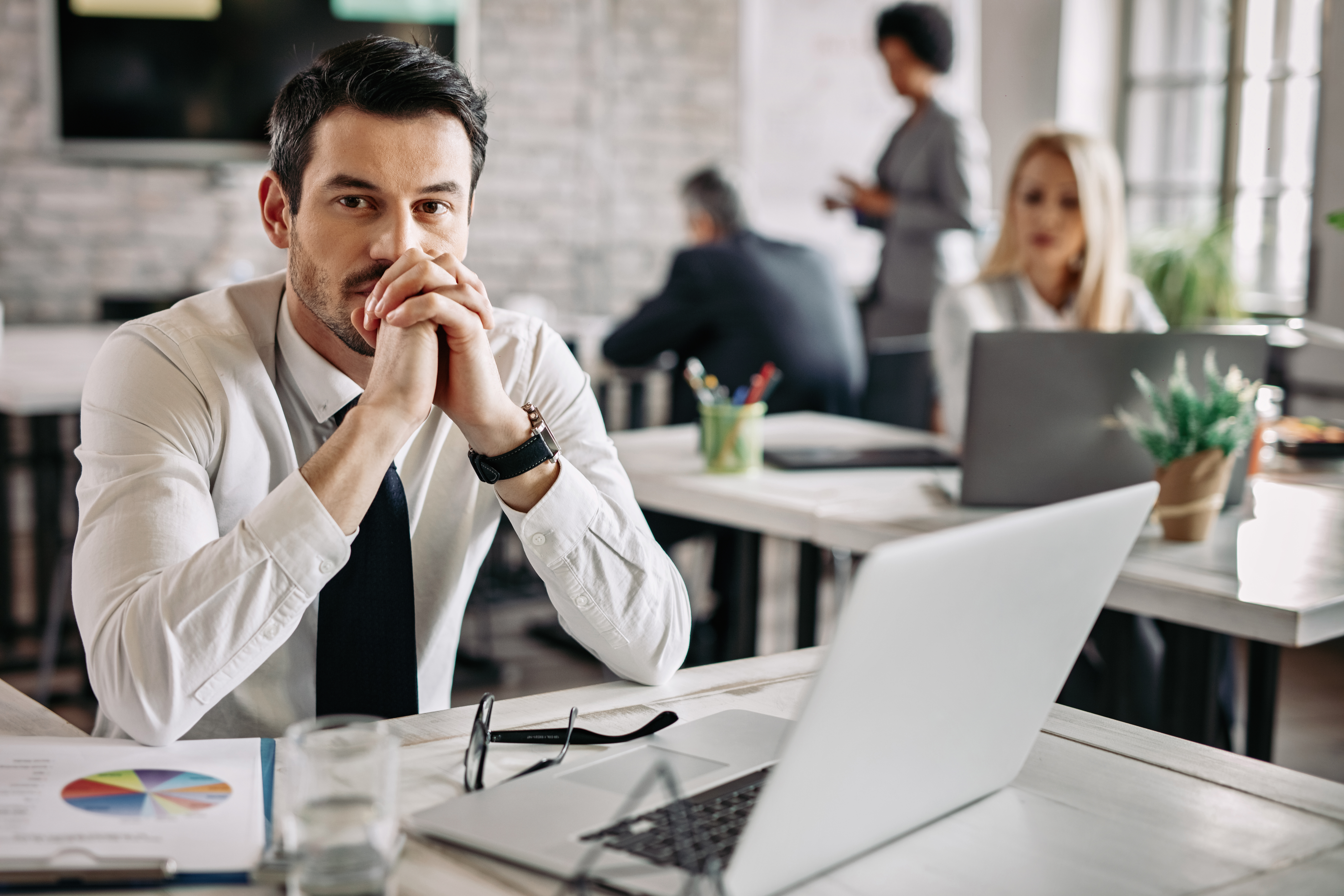 young-pensive-businessman-working-desk-office-thinking-something-there-are-people-background